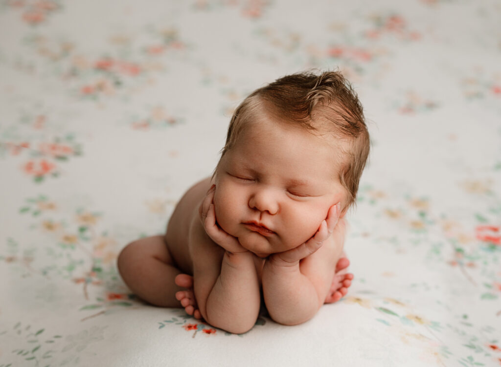 Colorado Springs newborn photography poses baby in froggy on floral backdrop. 