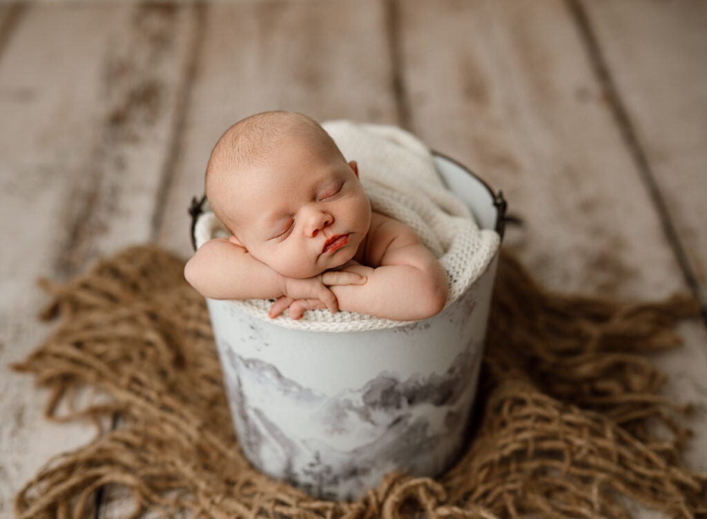 Colorado Springs Newborn Photography poses baby boy in bucket with mountains. 
